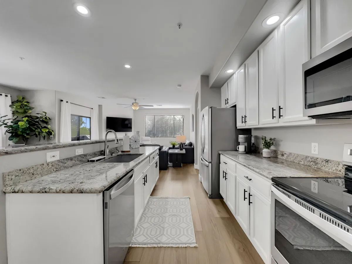 This modern kitchen shot highlights an open layout, granite countertops, and stainless steel appliances, with clear sight lines to adjacent gathering spaces. The kitchen exudes a sense of functionality and contemporary style, inviting guests to cook, entertain, or simply enjoy a meal together.