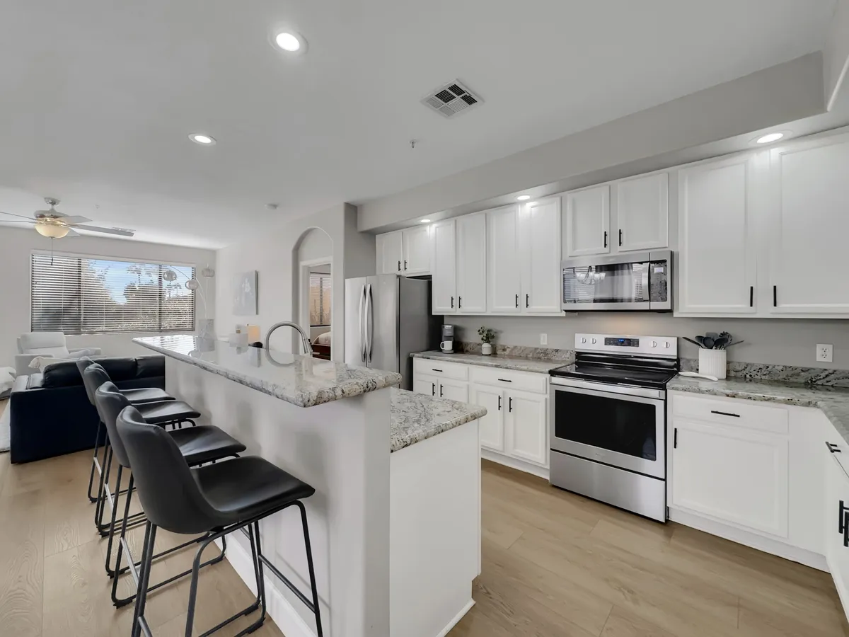 A modern chef’s kitchen featuring a spacious island, stainless steel appliances, granite countertops, and bar stools, exuding a welcoming ambiance perfect for entertaining or relaxing after a day out.