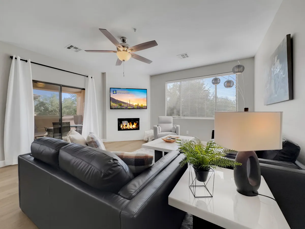 A stylish living room with a leather sofa, fireplace, TV, decorative lamp, and large window, creating a comfortable and inviting space for relaxation and entertainment.
